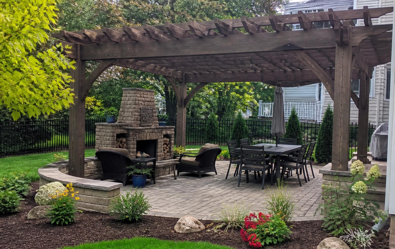 Wooden pergola over a stone patio surrounded by planting beds